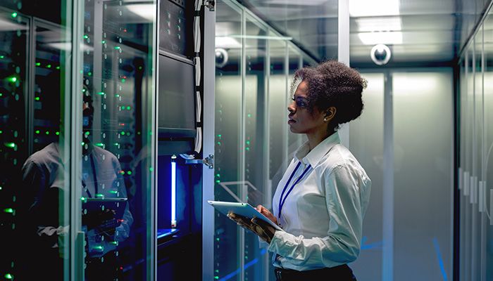 lady with laptop looking at servers in a data center
